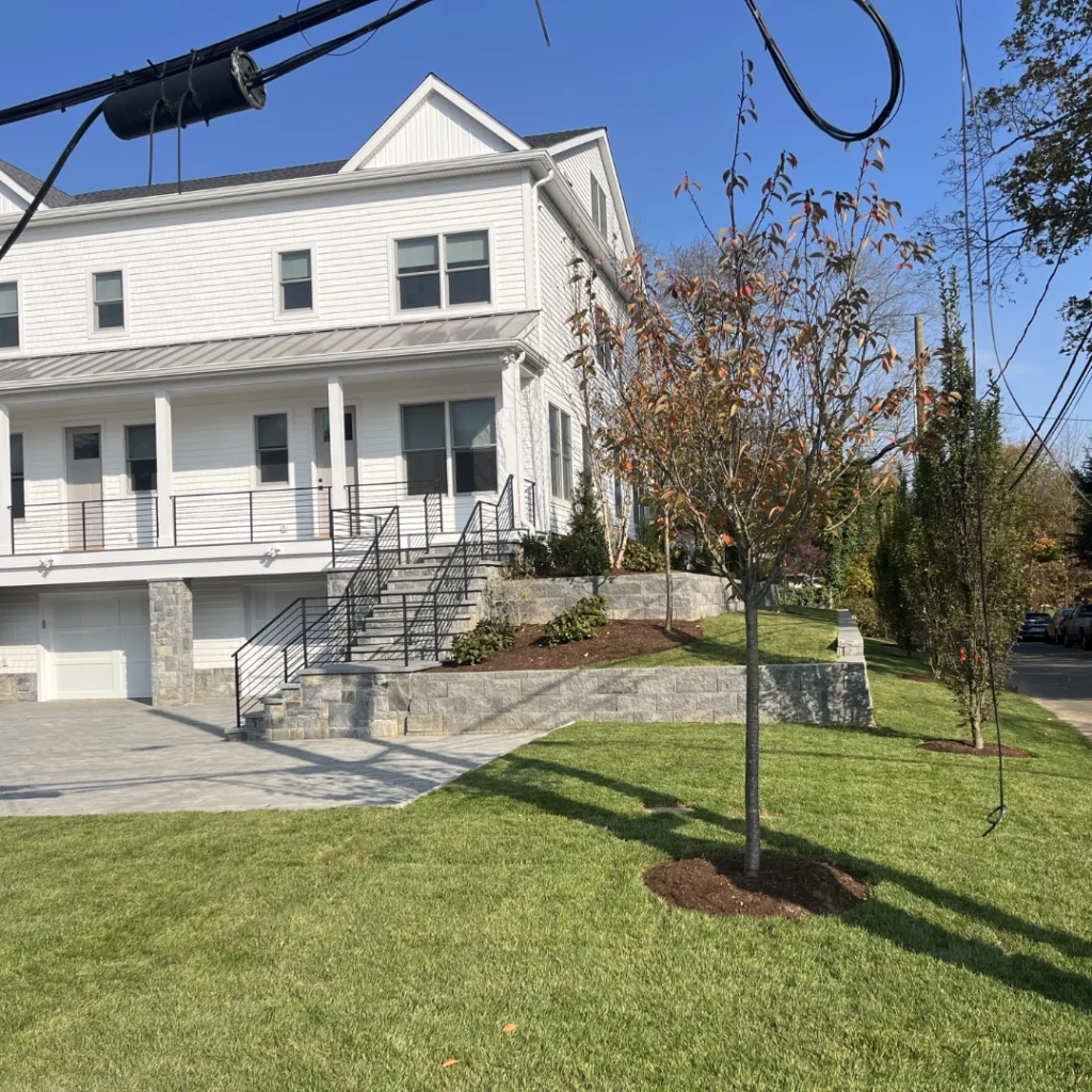 two family home with fresh cut grass, garden with mulch and trees with mulch